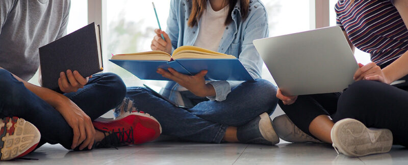 Student groups are viewing information in books and laptops.